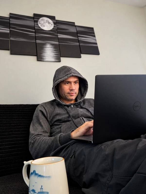 Candid photo of Justin Bazan working on GSA with a laptop and coffee.